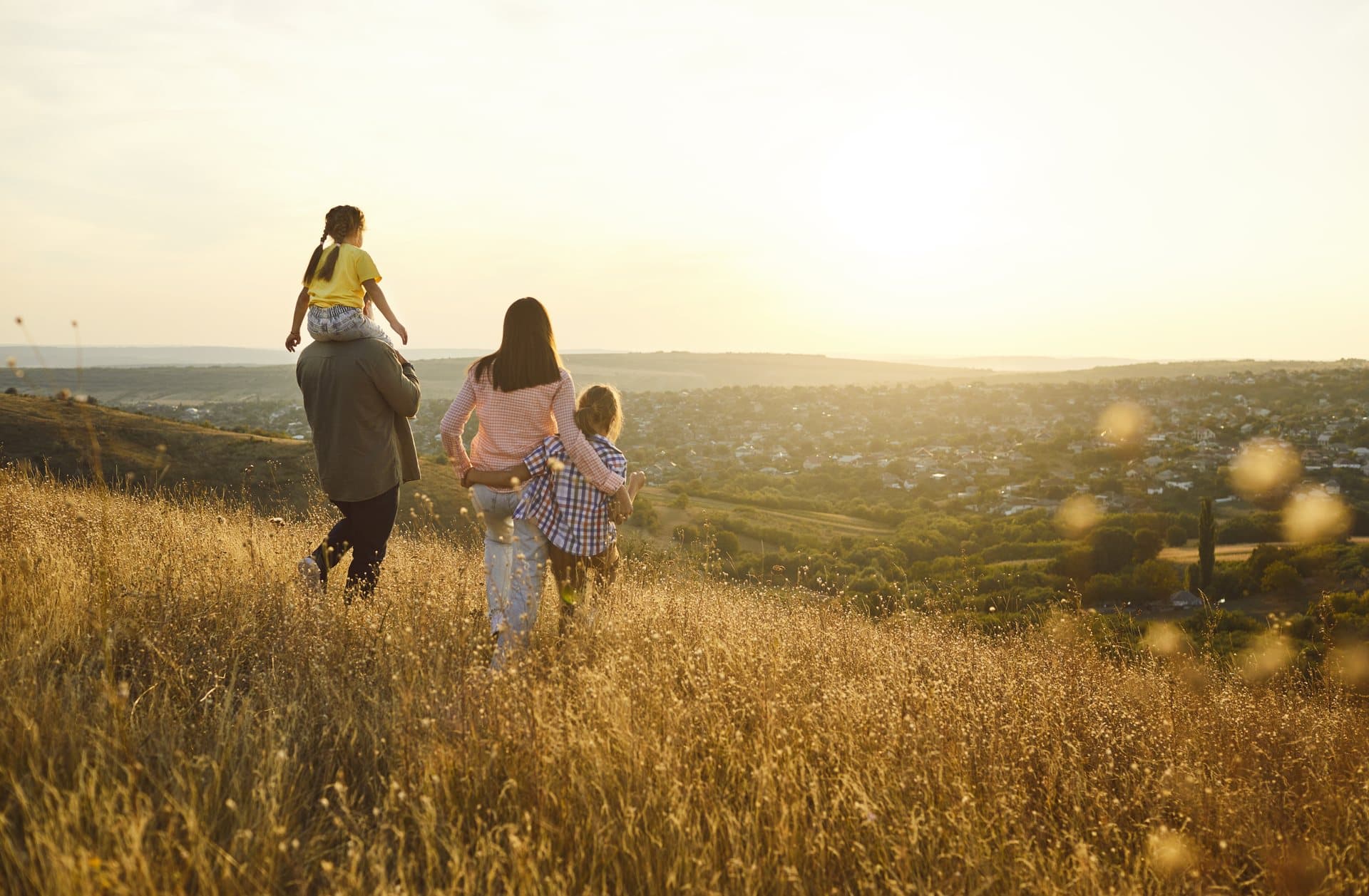 A family walking together through a sunlit field at dusk
